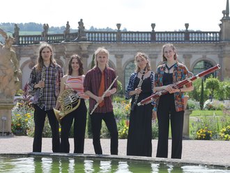 Jugendliche stehen im Schloss mit ihren Blasinstrumenten