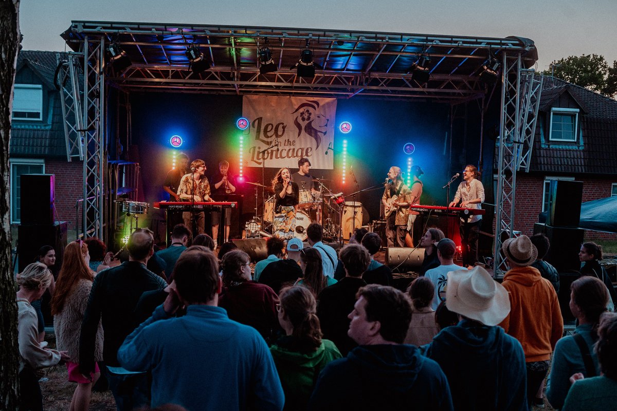 Menschen vor einer Bühne mit spielender Band in der Abenddämmerung