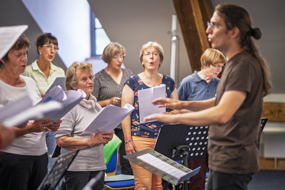 Chorleiter singt mit einer Gruppe Seniorinnen