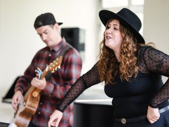 Gitarrenspieler im Hintergrund und Sängerin im Fordergrund