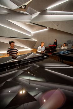 Zwei Personen spielen an zwei Konzertflügeln. Die riesigen Gesteinselemente an Decke und Wänden spiegeln sich in den Flügeldeckeln.